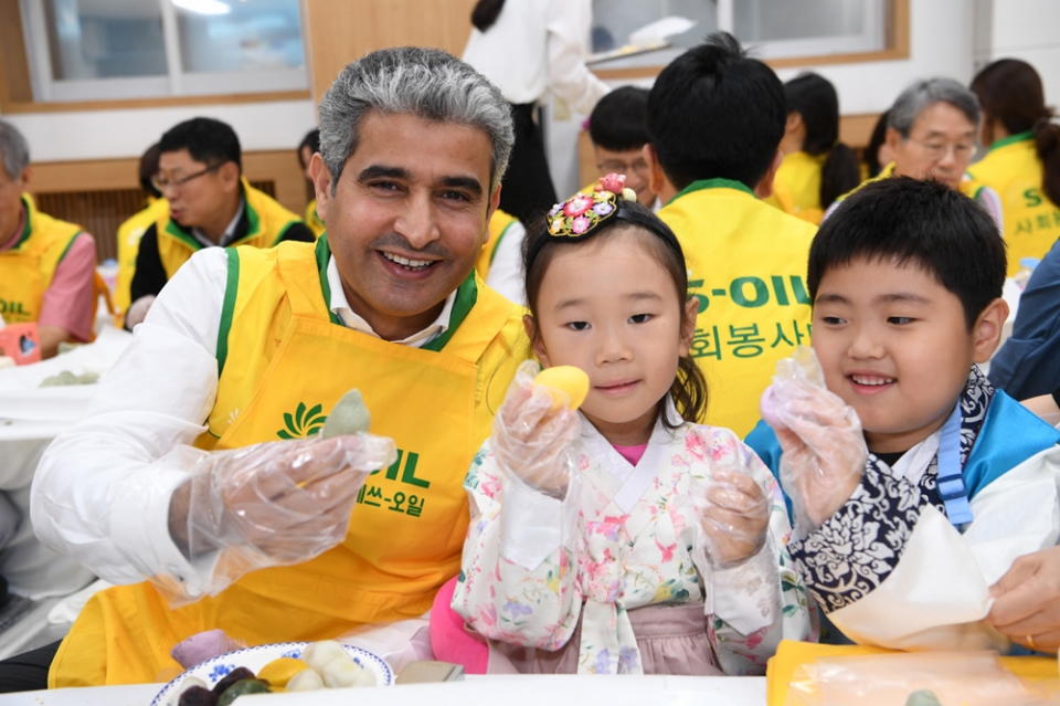 S-OIL CEO Hussain Al-Qahtani (far left) poses for the camera with children with  songpyeon that he himself made. (Courtesy of S-OIL)